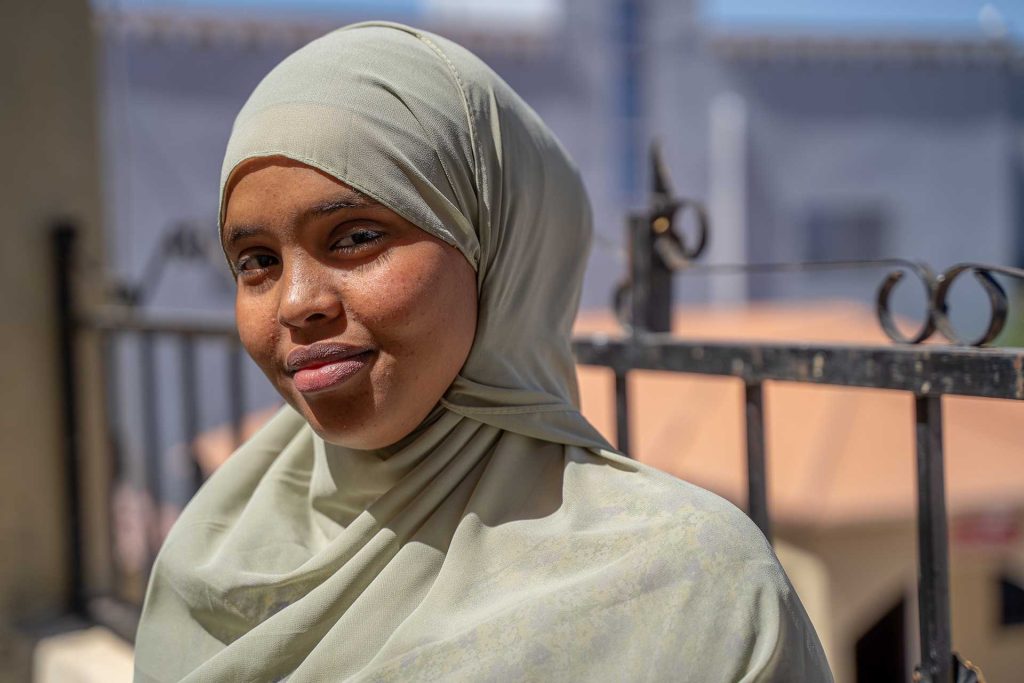 Somalimaalainen nainen katsoo hymyillen kameraan.