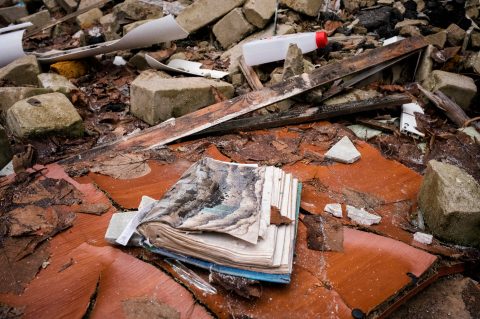 Lähikuva raketti-iskussa tuhoutuneesta koulusta. Kuvassa näkyy monenlaista iskun kohteena olleessa koulun luokkahuoneessa ollutta rikkoutunutta tavaraa. Etualalla on revennyt kirja.