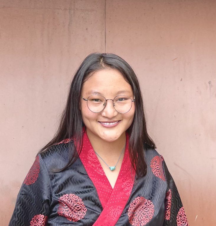A woman in a kimono wearing glasses looks at the camera while smiling