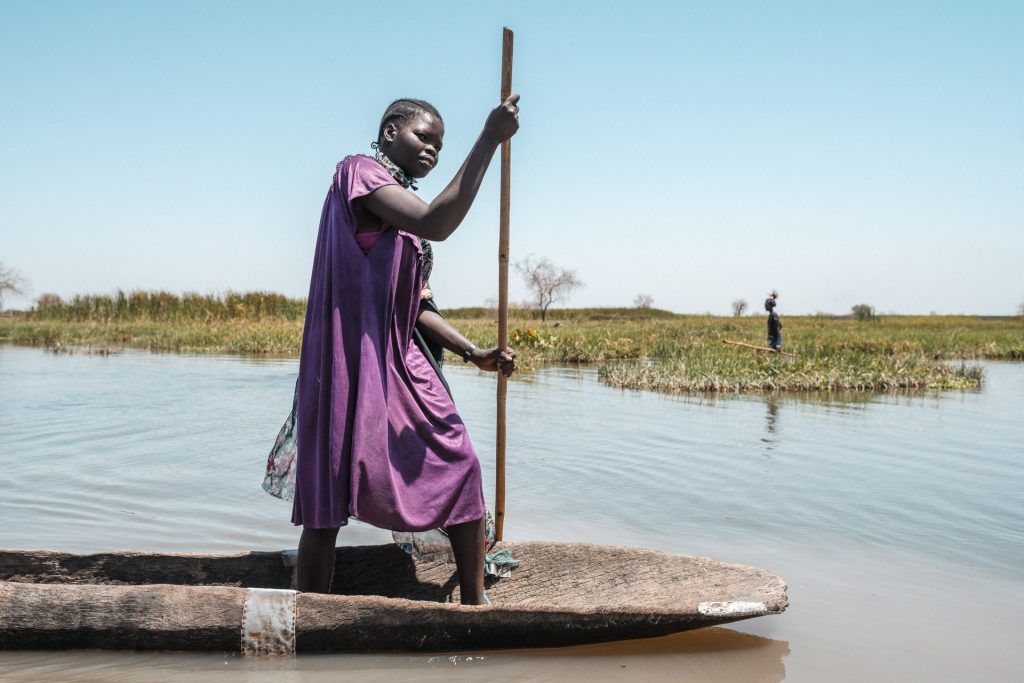 A woman stands in a wooden canoe