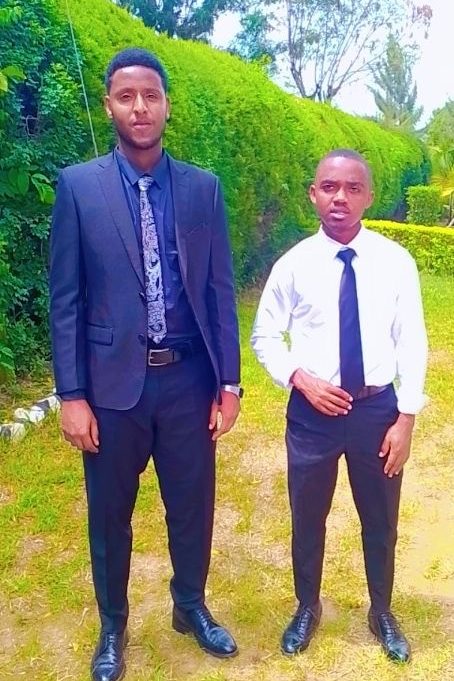 Two men in suits stand in a garden.