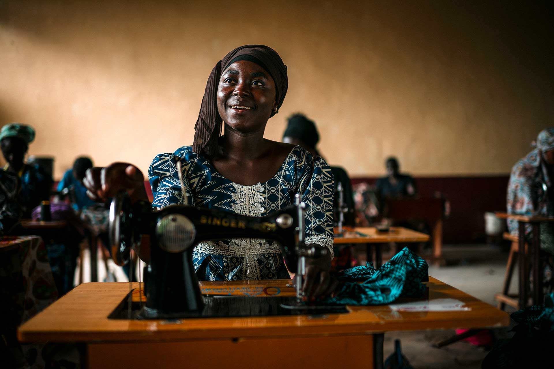 Nuori nainen istuu ompelukoneensa äärellä luokkahuoneessa Keski-Afrikan tasavallassa. A young woman sits at her sewing machine in a classroom in the Central African Republic.