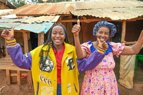 Two women poses with their thumbs up