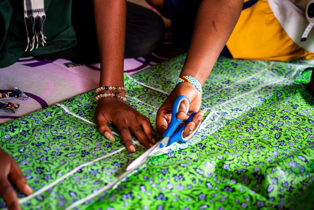 A womans hand cutting cloth with scissors.