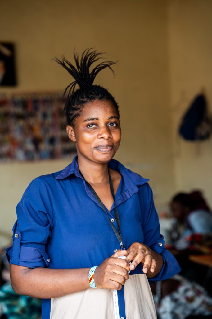 A woman in a sewing shop standing and smiling at the camera.