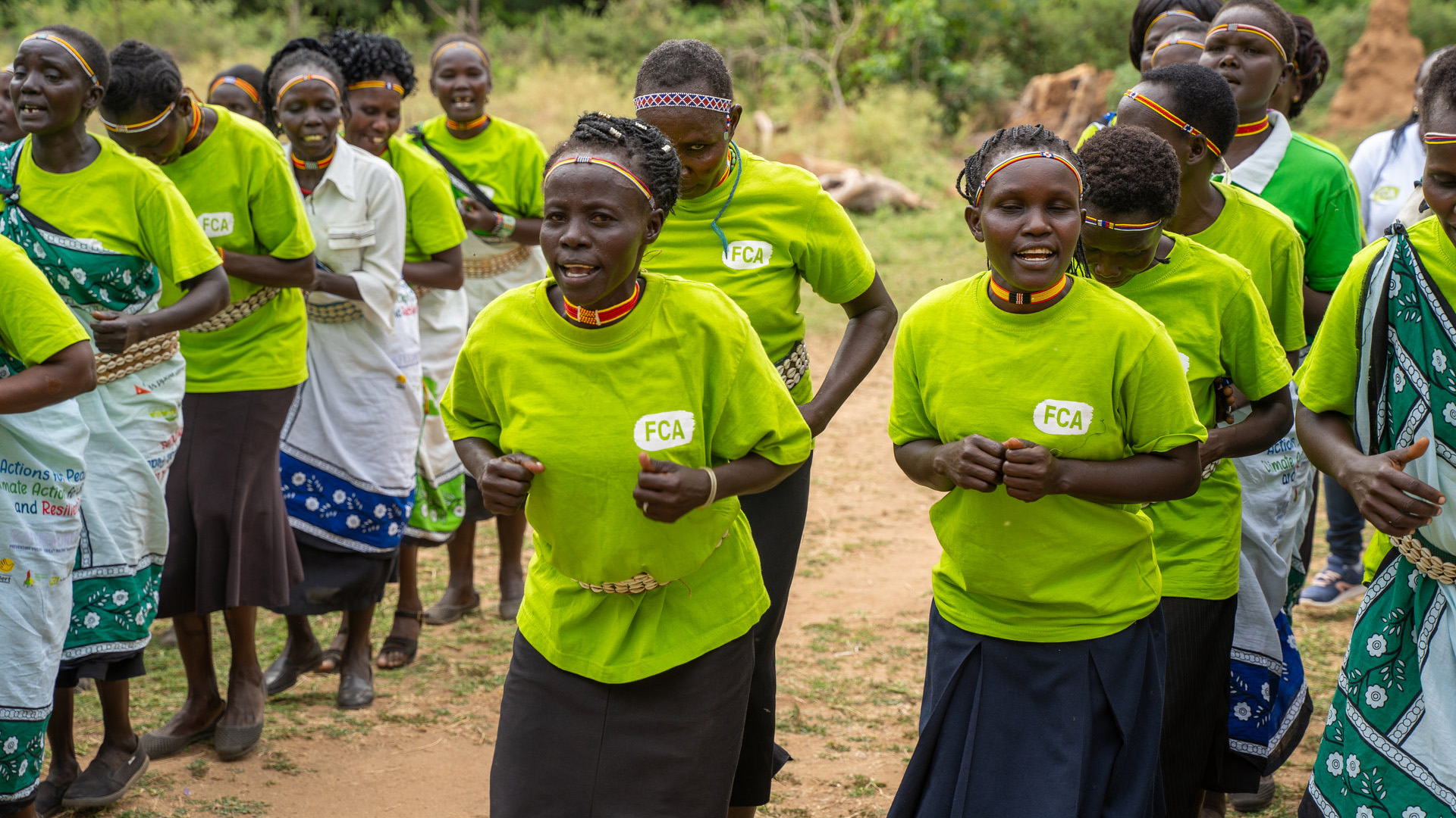 Women dressed in FCA shirts and kitenge dancing in lines.