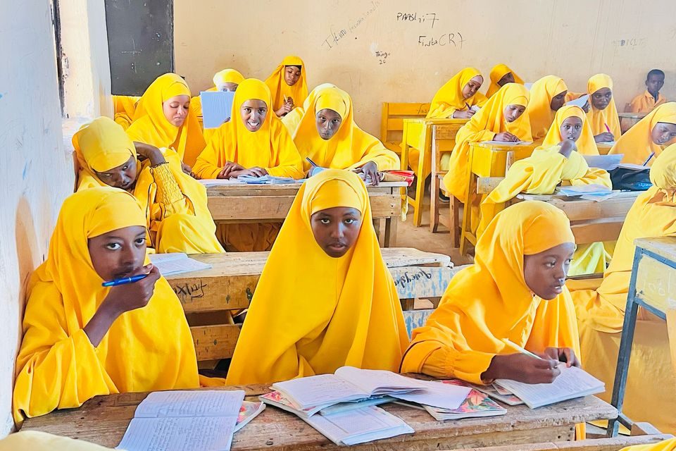 A classroom full of schoolgirls in yellow unifroms.