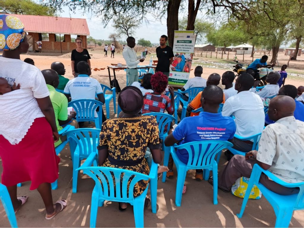 A number of people are sitting outside listening to a lesson