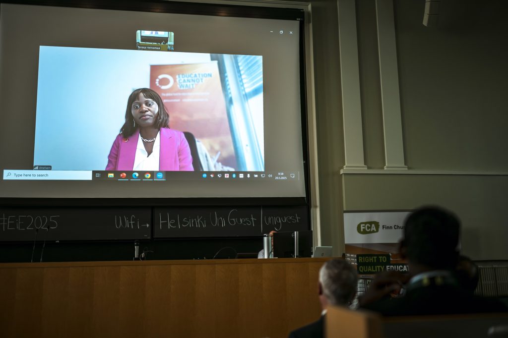 A woman on a screen addresses an auditorium