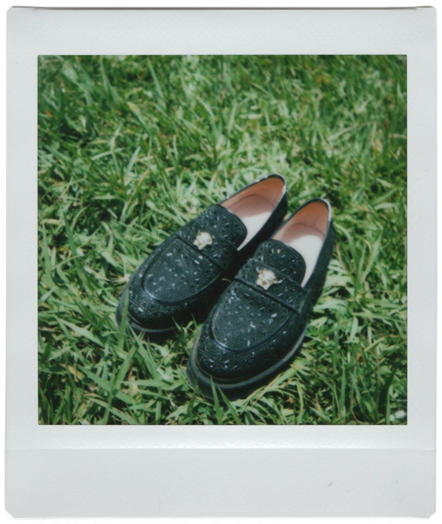 A polaroid photo of a pair of shoes lying on grass