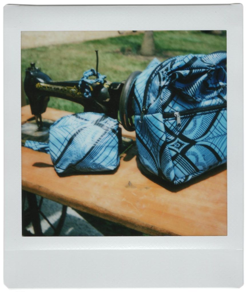 An old Singer sewing machine is on a table next to blue patterned fabric.