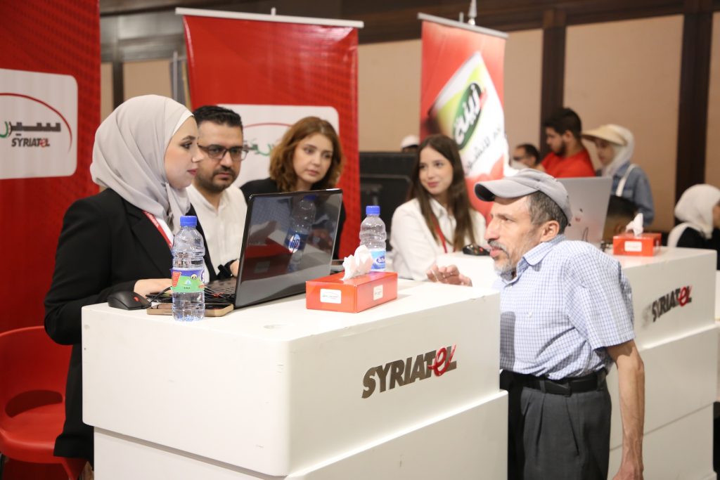 A man with a disability talks to a woman at a stand in a conference