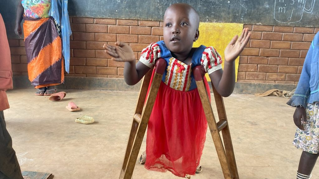 A girl sitting on her knees in a classroom, with crutches under her arms.