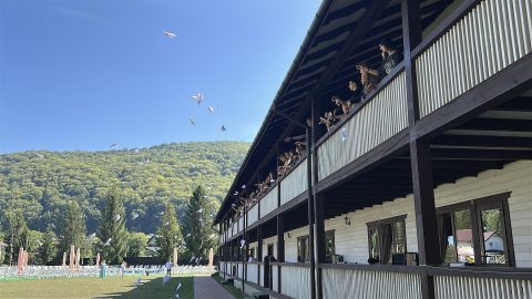Students stand on the top balcony of a holiday lodge and launch paper planes into the air.