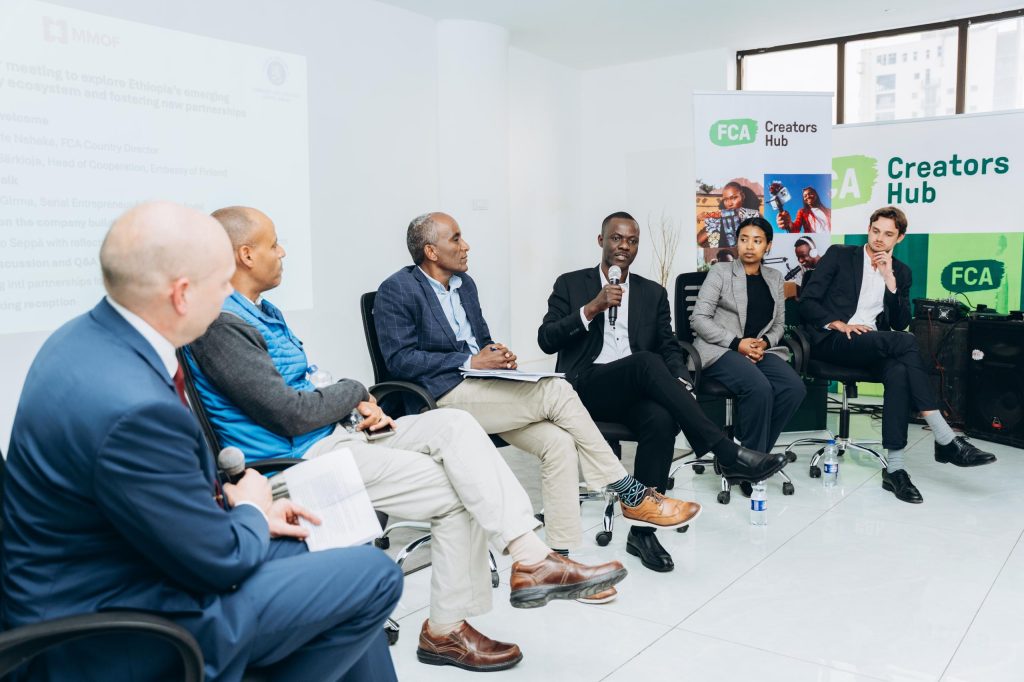 A man with a microphone talks to a panel of other people.