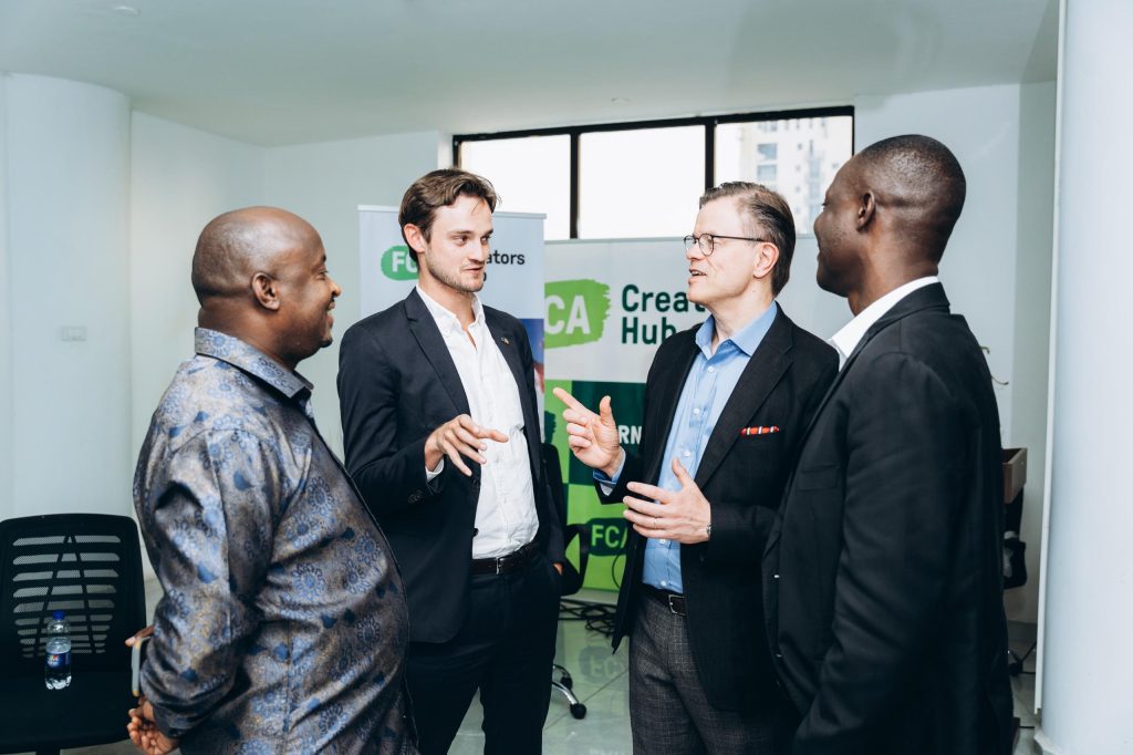 A group of four men in suits chat energetically