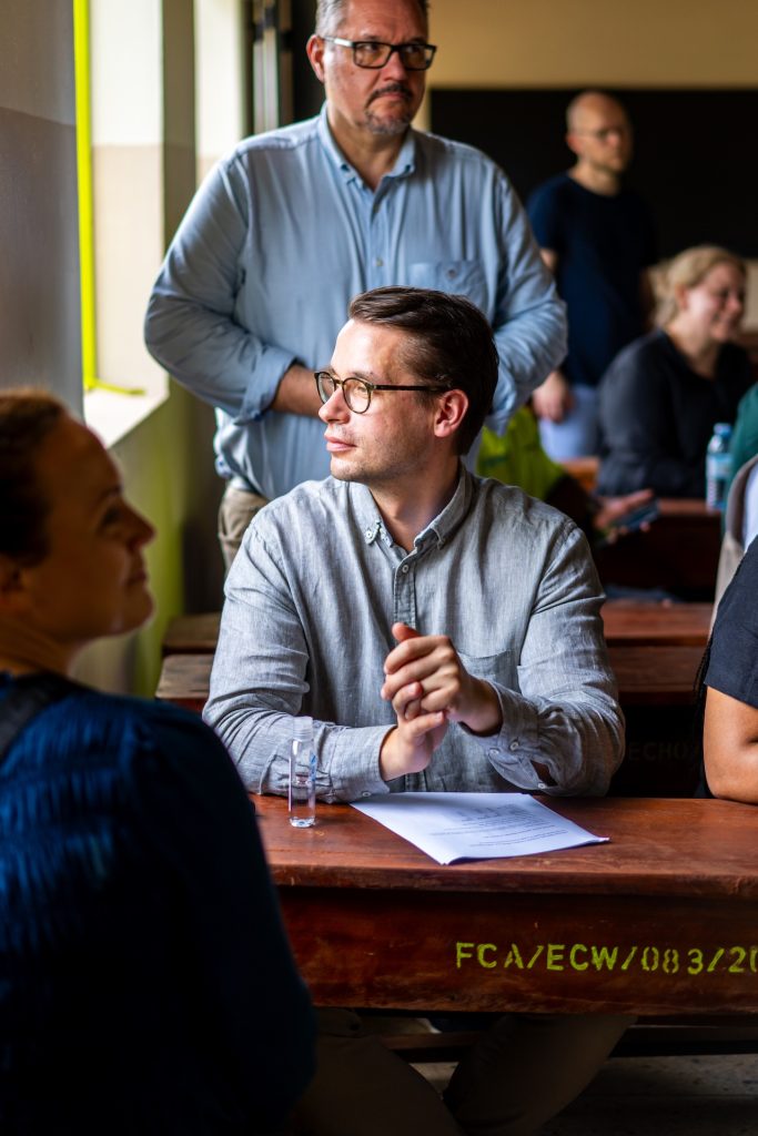 Mies istuu luokkahuoneen pulpetissa ja katsoo ikkunasta ulos.