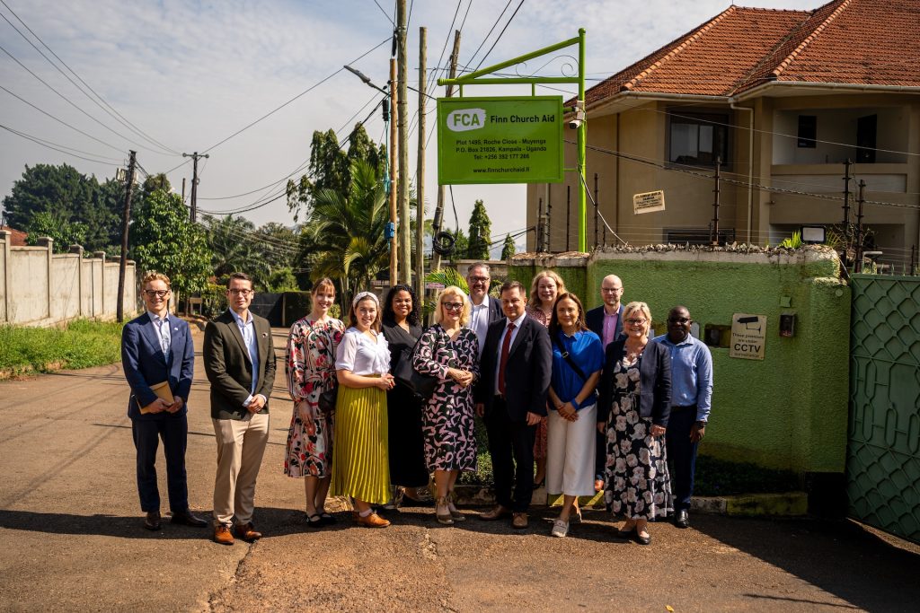Kolmetoista ihmistä seisoo Kirkon Ulkomaanavun ugandan toimiston ulkopuolella.