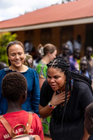 Kaksi naista puhuu lapselle koulun pihalla Ugandassa.