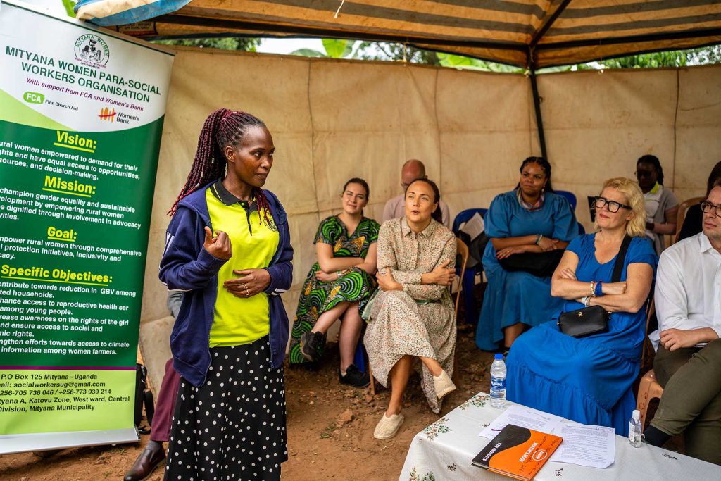 Nainen puhuu suomalaisille kansanedustajille, jotka istuvat telttakatoksessa.