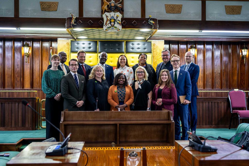 Joukko ihmisiä poseeraa Ugandan parlamentin istuntosalissa.