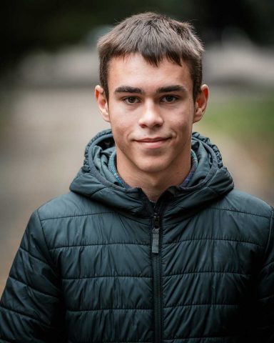 Nuori mies katsoo kameraan. 