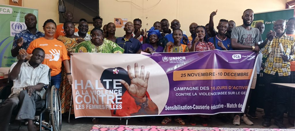 A number of people hold up a banner against gender-based violence. Some are in wheelchairs.