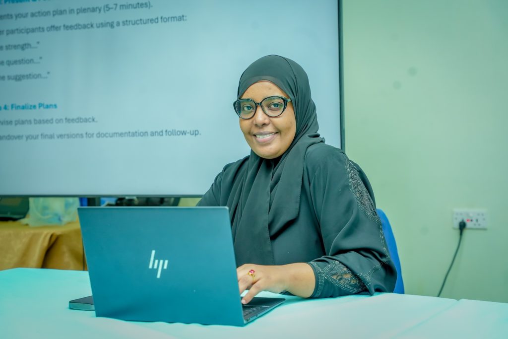 A smiling woman sits at a laptop