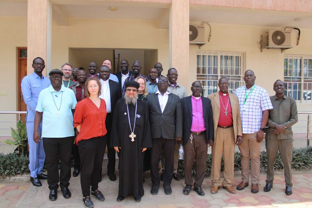 Joukko ihmisiä poseeraa valokuvassa rakennuksen portailla Etelä-Sudanissa.