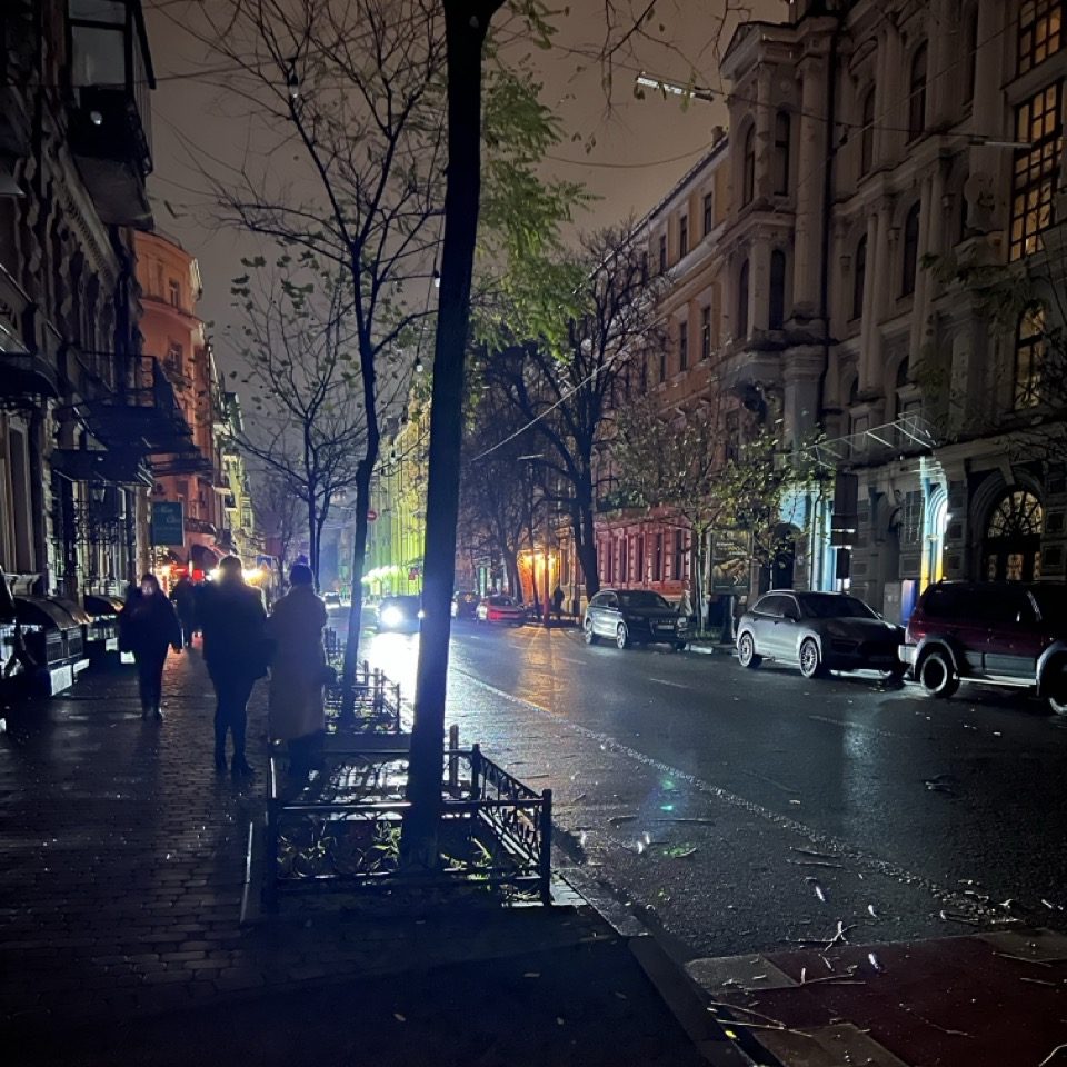 A dark city street only lit by a car's headlamps