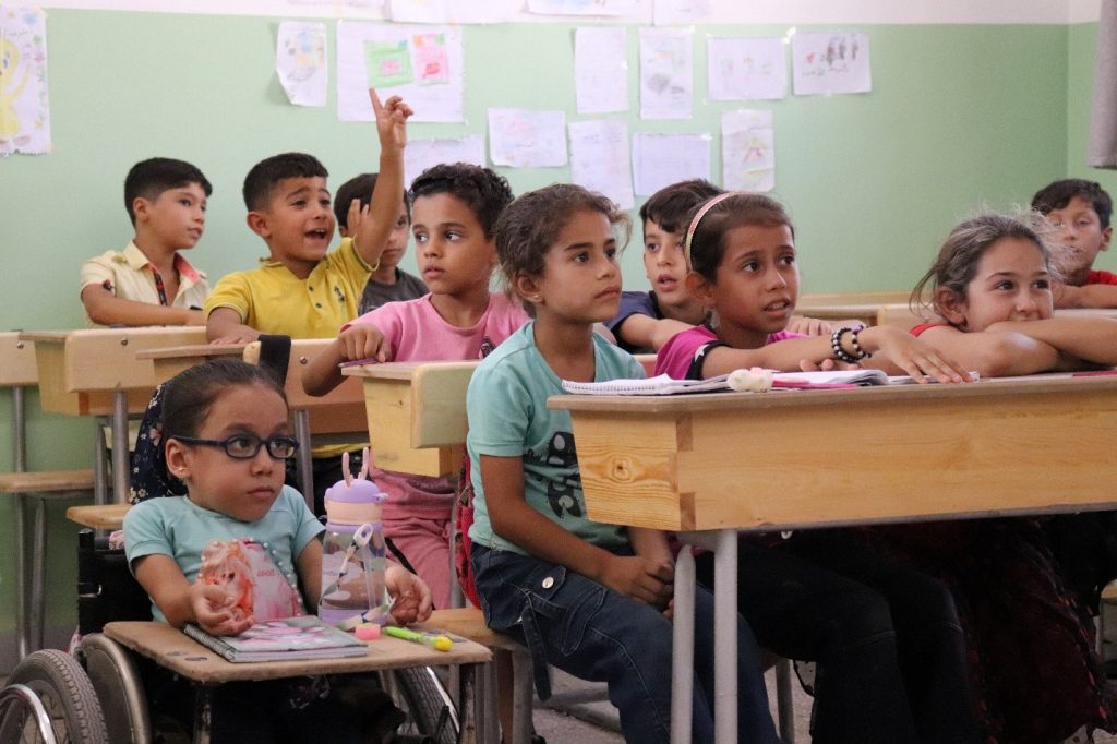 Classroom full of children sitting behind desks.