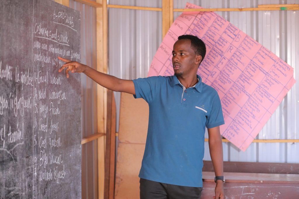 A man points to a blackboard