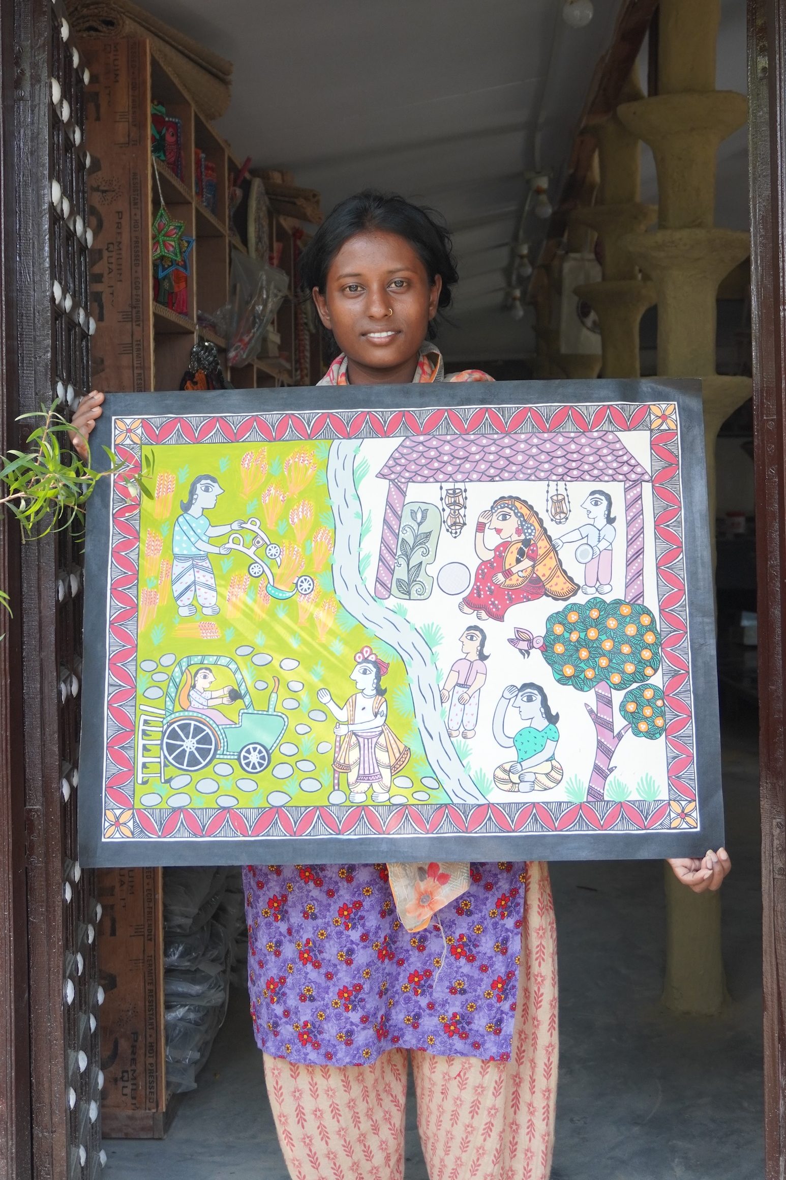 A young woman holds up a piece of traditional Mithila art.