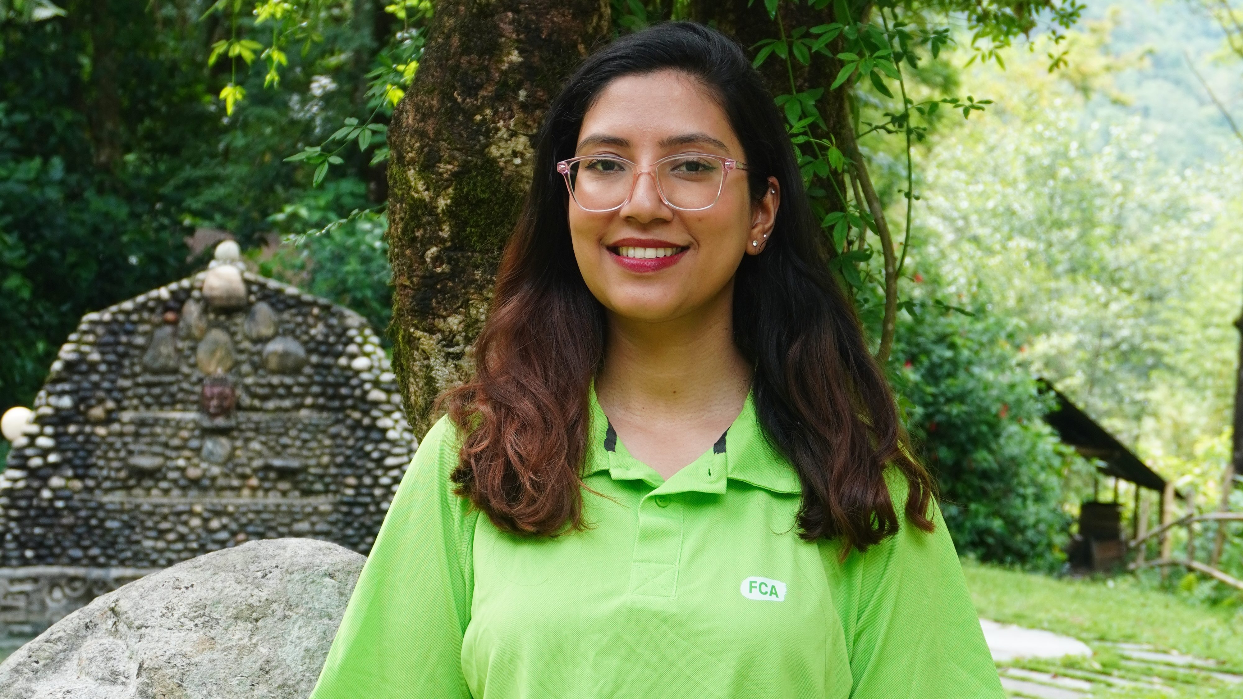A seated woman in a green FCA shirt smiles at the camera.