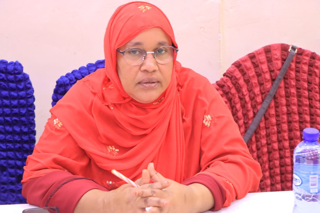 A woman in a red hijab sits at a desk