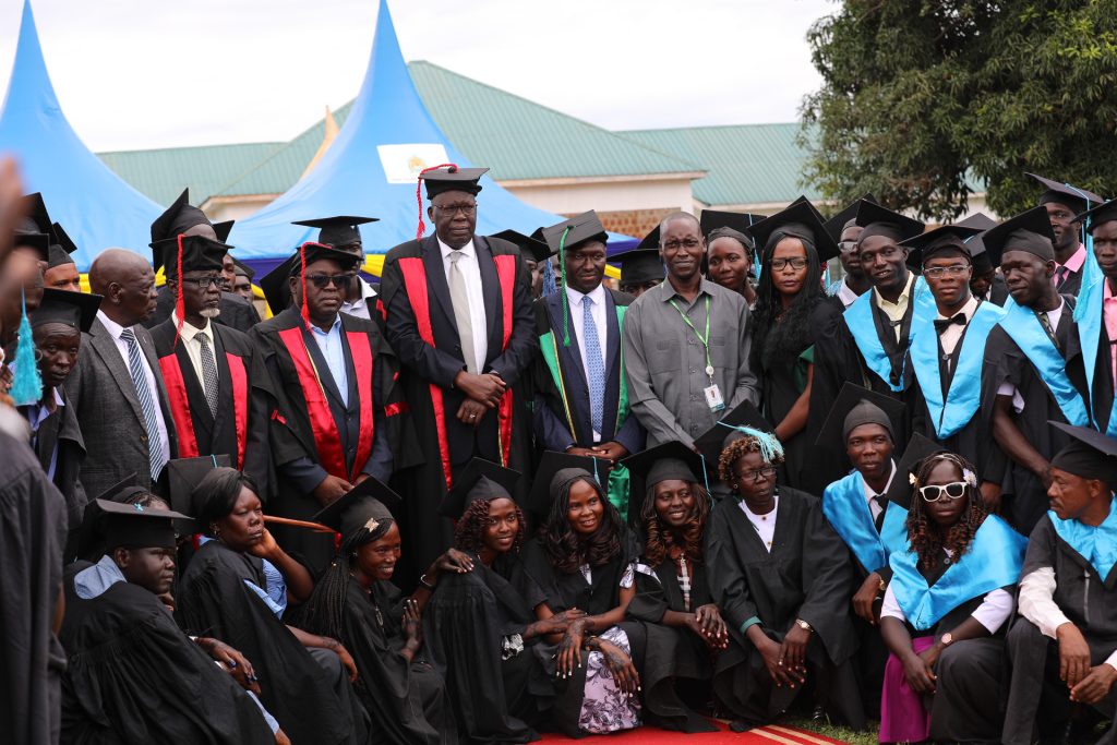 A large number of people in graduate caps and gowns are posing for a photograph