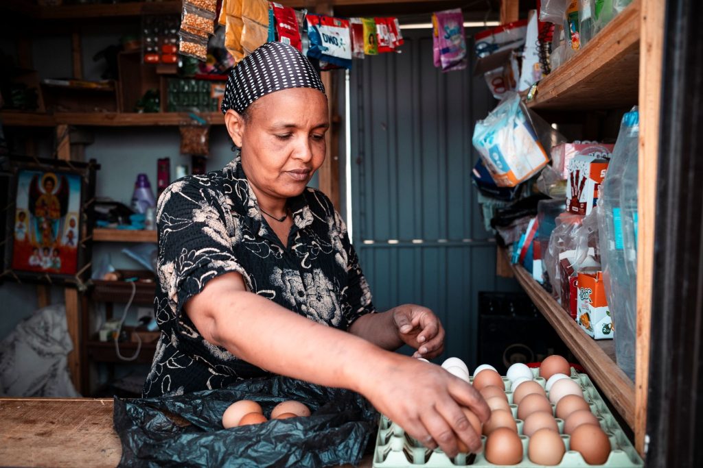 A woman in colorful outfit handeling eggs.